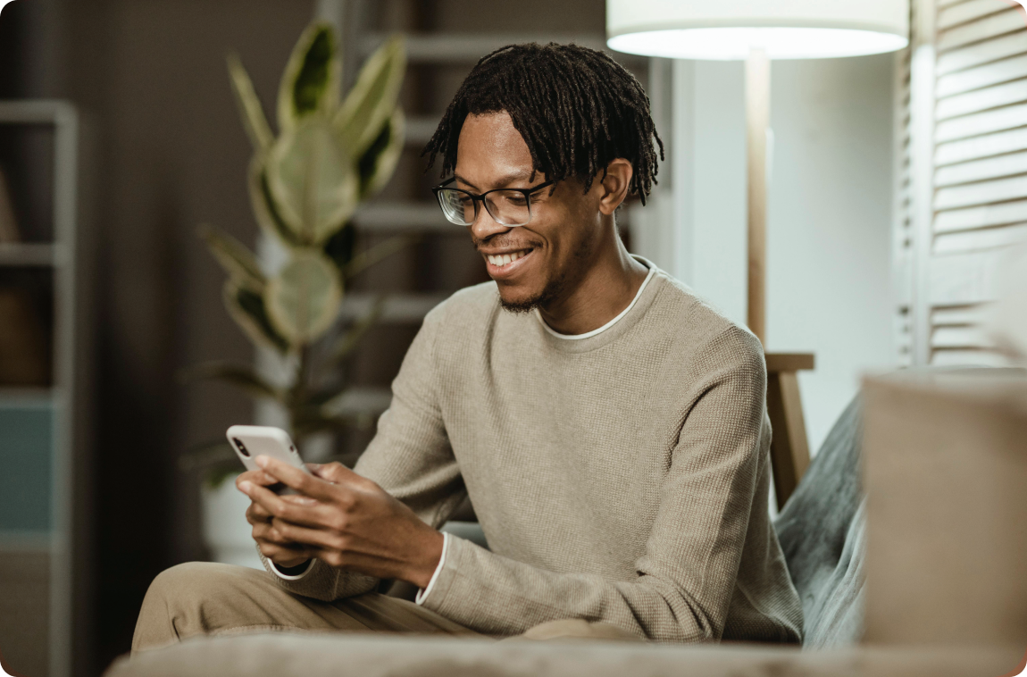 Homem Negro com Moletom Bege mexendo no celular